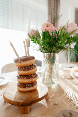 Alternatif doğum günü pastası olarak yaratıcı çörek kulesi. Çiçekler ve mumlarla süslü masa dekorasyonu, parti planlama, kutlama ve yaşam tarzı markalaşma kavramları için ideal.