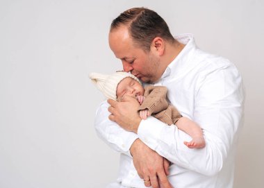 Genç baba kucağında bebeğini nazikçe öpüyor. Ebeveyn ve bebek arasındaki hassas babalık ve duygusal bağ anı.