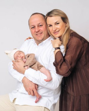 Yeni doğan kızlarını bir arada tutan genç ebeveynlerin portresi. Anne, baba ve çocuk arasındaki aile mutluluğu, ebeveynlik ve duygusal bağ kavramı.