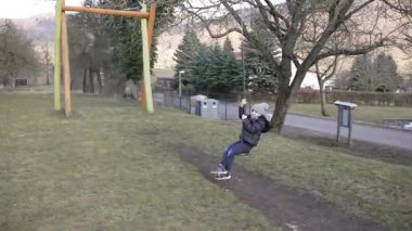 Çocuk dışarıda oyun saatinde parkta ip cambazlığı yapıyor. Oyun alanı ekipmanlarında hareketlilik, eğlence ve eğlence gösteren dinamik çocukluk aktiviteleri.