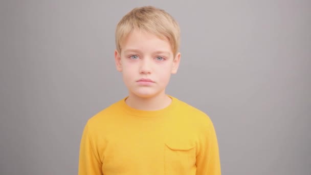 Little girl is surprised looking into the camera. Picture taken in the studio on a gray background. Super slow motion. — Stock Video