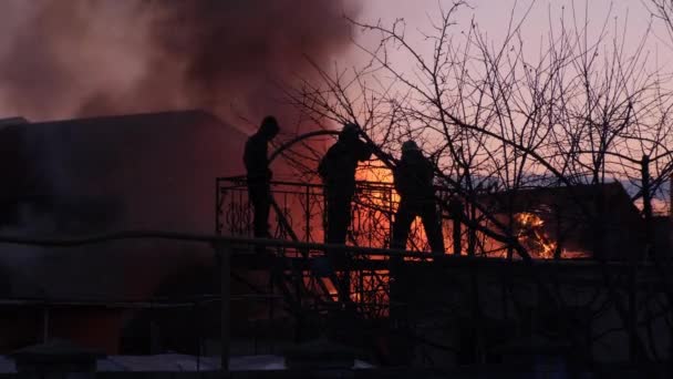 Brandmän släcker ett privat hus. Stugan brinner, flammorna sprider sig genom huset. — Stockvideo