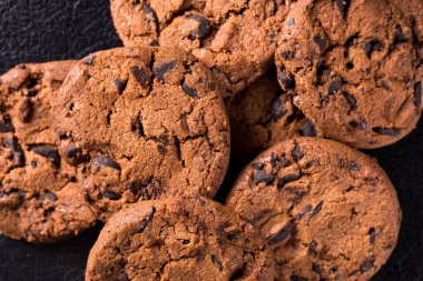 Siyah arka planda kuru üzümlü çikolata parçacıklı kurabiyeler..