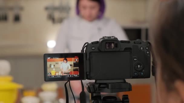 La muchacha el cocinero graba el vídeo de las recetas de cocina. Adorable mujer hablando grabación cocina video en cocina interior. — Vídeo de stock