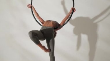 Beyaz arka planda, gölgeli akrobatik bir yüzükteki kız jimnastikçi..