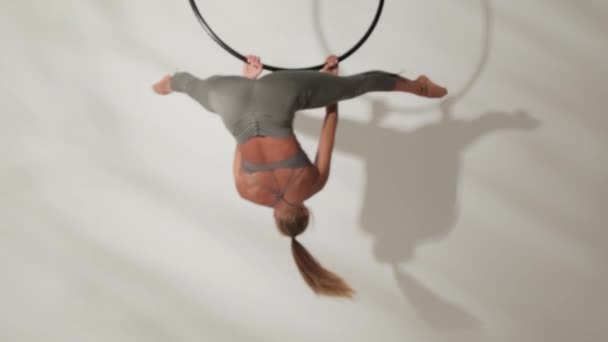 Flicka gymnast på en akrobatisk ring på en vit bakgrund med skuggor. — Stockvideo