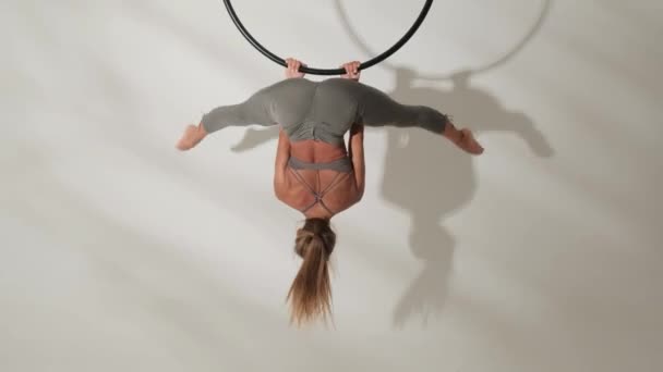 Flicka gymnast på en akrobatisk ring på en vit bakgrund med skuggor. — Stockvideo
