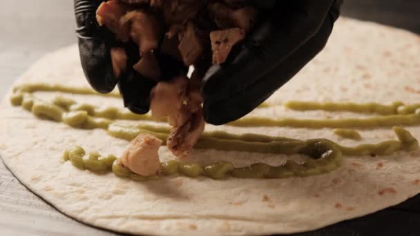 Tortilla těsto je obaleno kuřecí zeleninou a sýrem. Quesadilla s kuřecím masem na černém pozadí zblízka. — Stock video