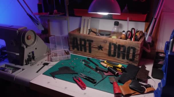 Home workshop voor het maken van lederen accessoires in neon licht. Naaien en repareren van kleding tijdens quarantaine en pandemie. — Stockvideo