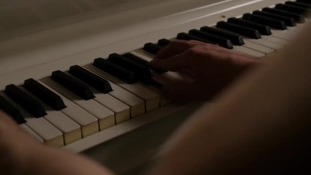 Een man speelt witte piano. man handen close-up op de piano toetsen. — Stockvideo