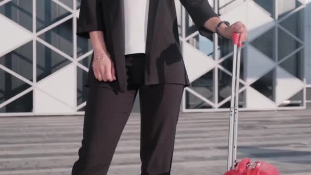 Affärskvinna i kostym och en röd resväska på flygplatsen en varm sommardag. — Stockvideo