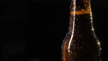 Siyah arka planda su damlaları olan bir şişe bira..
