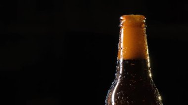Siyah arka planda su damlaları olan bir şişe bira..