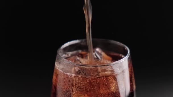 Bebida fría gaseosa en un vaso con cubitos de hielo de cerca sobre un fondo negro. — Vídeo de stock