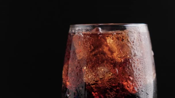 Bebida fría gaseosa en un vaso con cubitos de hielo de cerca sobre un fondo negro. — Vídeos de Stock