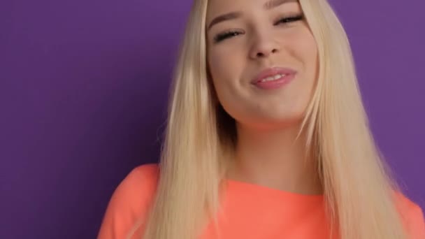 Krásná blondýna s pozitivními a veselými emocemi. Dívka na fialovém pozadí ve studiu se raduje a usmívá — Stock video