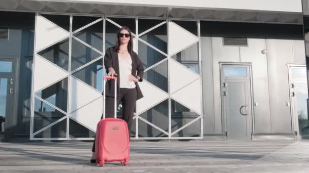 Una chica con un traje de negocios negro y una maleta roja está abordando el avión. Maleta roja equipaje de mano. — Vídeos de Stock