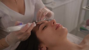 Cometolojik prosedür geçiren bir kız. Güzellik uzmanından yüz bakımı. Profesyonel ultrasonik yüz temizliği..