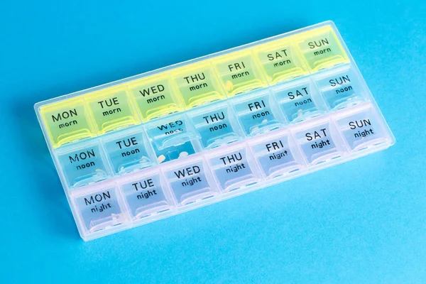 Arrangör för medicinska piller på en blå isolerad bakgrund närbild. Organisation av ta piller för dagen. — Stockfoto