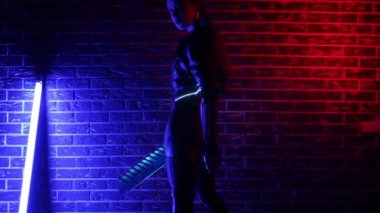 Neon renkli ışıkta siber punk gibi giyinmiş bir kız. Parlayan kılıç ve kontakt lensler.