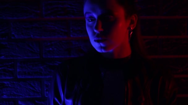 Portré egy kiberpunk jelmezes lányról neon színű fényben. Ragyogó kard és kontaktlencse. — Stock videók