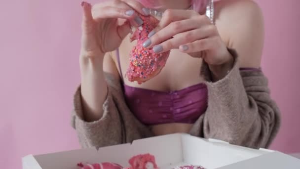 Young brunette woman enjoys eating a sweet bright donut. Smiling girl with food close-up. — Stock Video