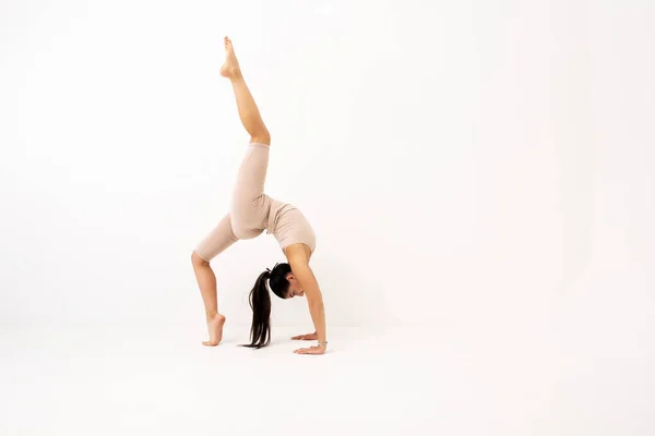 Fille faisant étirement dans le studio sur un fond blanc. Une belle gymnaste au corps souple et à l'uniforme sportif. — Photo