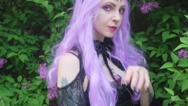 Ninfa com cabelo roxo na floresta com flores lilás. — Vídeo de Stock