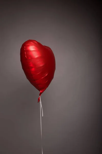 Bola vermelha com hélio na forma de um coração em um fundo cinza — Fotografia de Stock