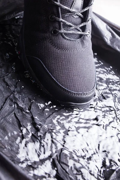 Sneakers da uomo nere con gocce d'acqua, primo piano su sfondo nero isolato . — Foto Stock