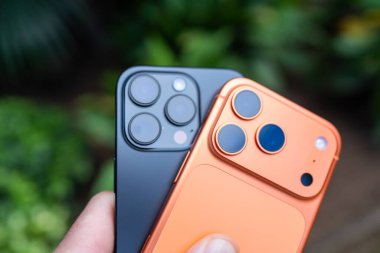 Tarragona, İspanya - 26 Ekim 2025: Elinde turuncu iPhone 16 Pro ve 17 Pro tutan bir adamın yakın çekimi.