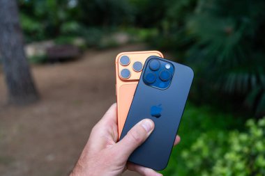 Tarragona, İspanya - 26 Ekim 2025: Bir adam elinde turuncu bir iPhone 16 Pro ve 17 Pro tutuyor.