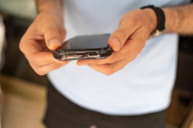 Telefonuna şok geçirmez koruyucu bir çanta takan bir adamın yakın çekimi..