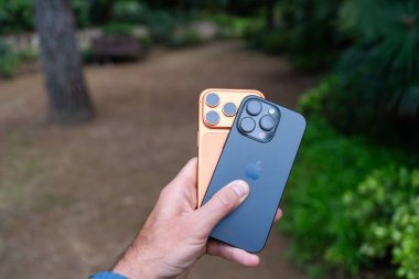 Tarragona, İspanya - 26 Ekim 2025: Bir adam elinde turuncu bir iPhone 16 Pro ve 17 Pro tutuyor.