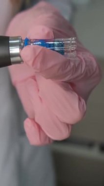 Bir güzellik kliniğinde gelişmiş cilt bakımı ve estetik tedavide kullanılan pembe tıbbi eldivenlerde tutulan profesyonel mikro donanım..