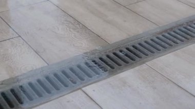 Kapalı hava kanalizasyon ızgarası. Yağmurdan sonra fayanslı yüzeyde su birikintisi var..