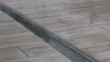 Kapalı hava kanalizasyon ızgarası. Yağmurdan sonra fayanslı yüzeyde su birikintisi var..