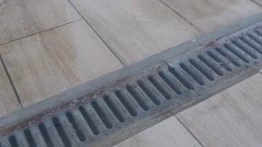 Kapalı hava kanalizasyon ızgarası. Yağmurdan sonra fayanslı yüzeyde su birikintisi var..