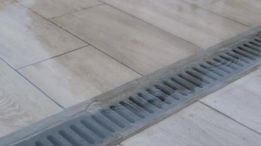 Kapalı hava kanalizasyon ızgarası. Yağmurdan sonra fayanslı yüzeyde su birikintisi var..