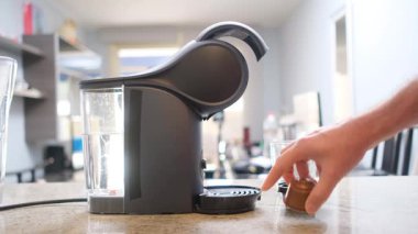 Cam bardak ve kahve kapsülü ile kapsül kahve makinesinin yakın çekimi, hızlı ve kullanışlı kahve hazırlama.