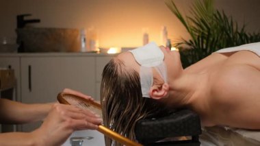 Kuaför salonunda uzanan beyaz bir adam, serinletici pedlerle kaplı gözler, lavaboda ıslak saçlarda şampuan yıkayan bir stilist, sıcak.