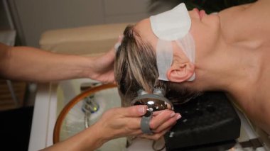 Profesyonel kozmetik uzmanı, lüks bir güzellik salonunda bir kadının ıslak saçlarını yıkayıp tarıyor.