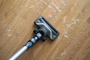 Elektrikli süpürge hortumu meşe ağacından dökülen pirinç tanelerini emiyor. Ev temizliğini ve ev işlerini gösteriyor.