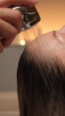 Beyaz kadın mum ışığında japon spa 'sında saç yıkama, durulama ve masajda el yapımı duşla kafa derisini yüzüyor.