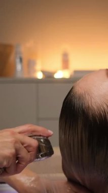 Beyaz kadın mum ışığında japon spa 'sında saç yıkama, durulama ve masajda el yapımı duşla kafa derisini yüzüyor.