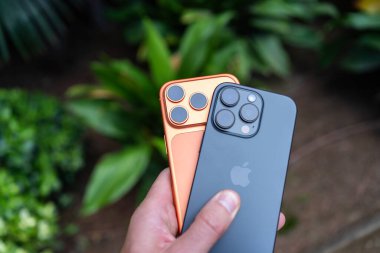 Tarragona, İspanya - 26 Ekim 2025: Bir adam elinde turuncu bir iPhone 16 Pro ve 17 Pro tutuyor.