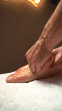 Erkek masör derin doku ayak masajı yapıyor. Profesyonel terapist tabana baskı uyguluyor, gevşemeyi ve sağlığı destekliyor.