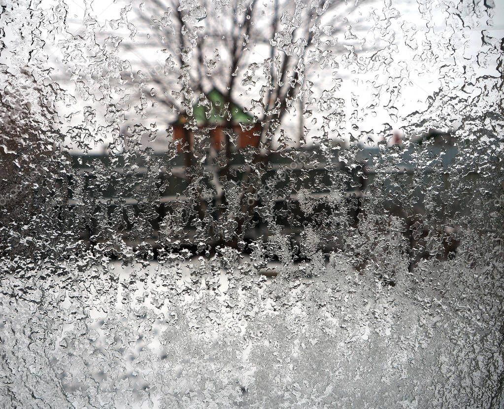 ice floes on the window against the blurry landscape of the garden