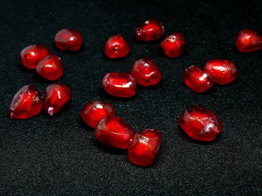 Siyah zemin üzerinde olgun nar taneleri, dar odak alanı, tanecikler değerli yakut ya da kırmızı yakut gibi parlar.