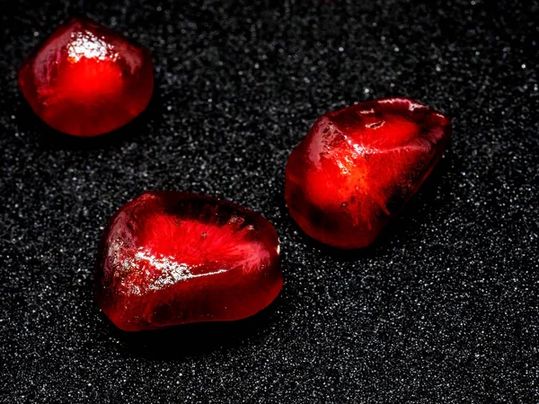 成熟石榴的红色颗粒 背景为黑色 聚焦点狭窄 晶莹如散落的珍贵红宝石或红色石榴石 — 图库照片